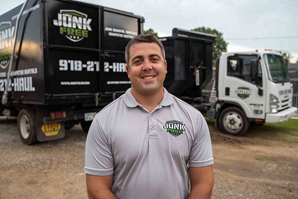 Junk Free LLC founder in front of junk removal trucks