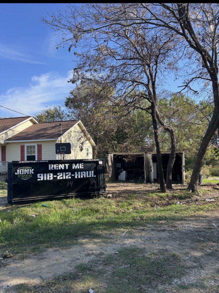 Junk Free 15-yard roll-off dumpster beside a house and garage