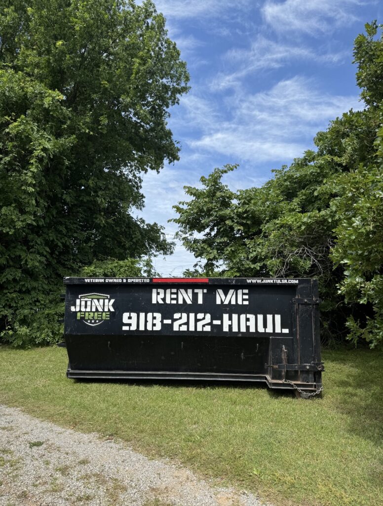 Junk Free 15-yard roll-off dumpster on grass beside trees