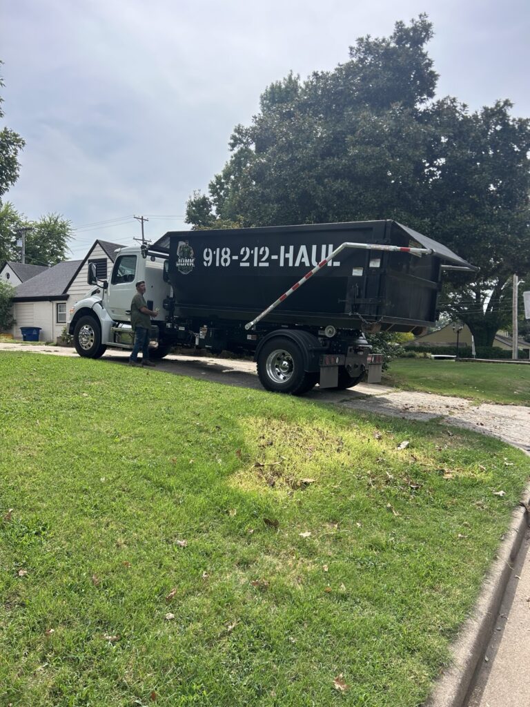 Junk Free truck carrying a black 20-yard roll-off dumpster