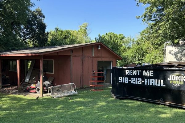 Black Junk Free roll-off dumpster beside a house during a residential cleanup
