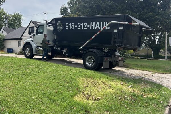 Junk Free truck carrying a black 20-yard roll-off dumpster